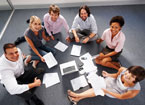 circle of people working around computer on floor