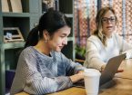 Photo of two people discussing something on a laptop.